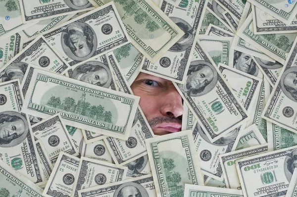 Man looking through a hole between dollar bills — Stock Photo, Image