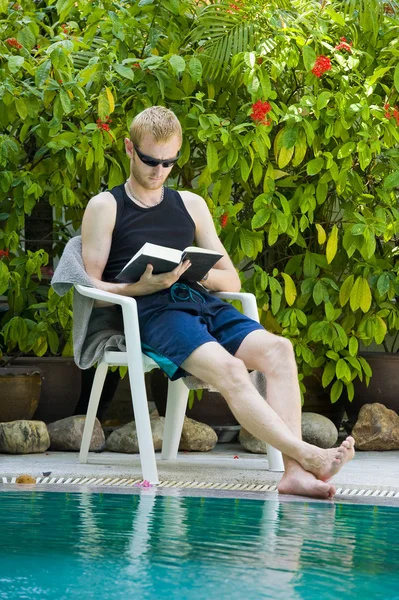 Νεαρός άνδρας ανάγνωση εδώ κοντά η πισίνα — Φωτογραφία Αρχείου