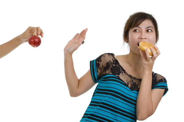Mujer con hamburguesa rechazando una manzana — Foto de Stock