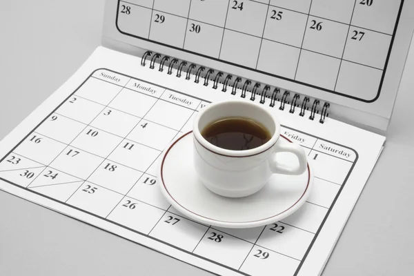 Koffiekopje op kalender Rechtenvrije Stockafbeeldingen