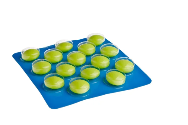 Zielone tabletki w niebieskim opakowaniu. — Zdjęcie stockowe