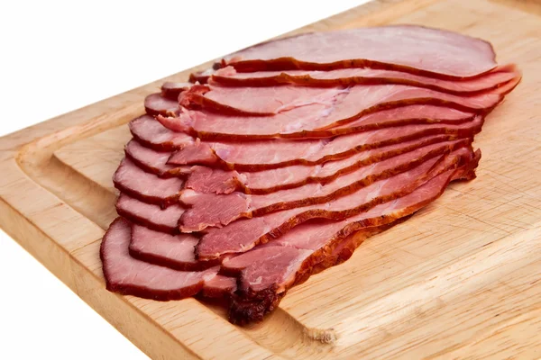 Gerookte ham segmenten op houten bord. — Stockfoto