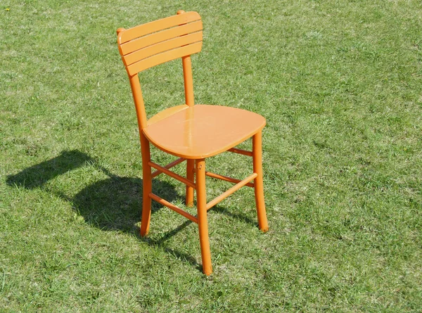 stock image Orange wooden chair on grass