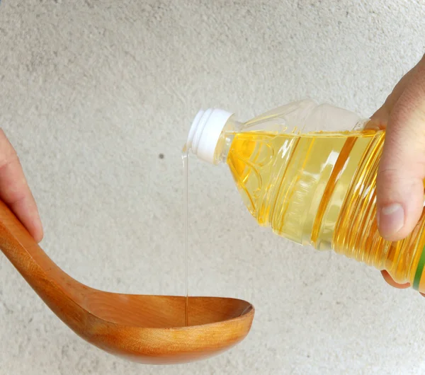 Pouring oil into wooden spoon — Stock Photo, Image