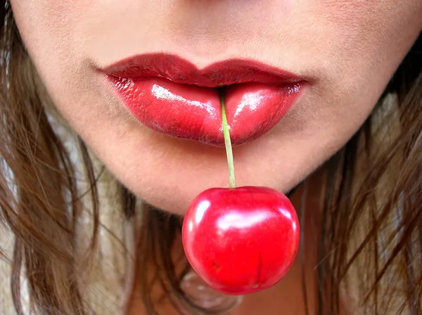 Cereja vermelha em lábios vermelhos — Fotografia de Stock