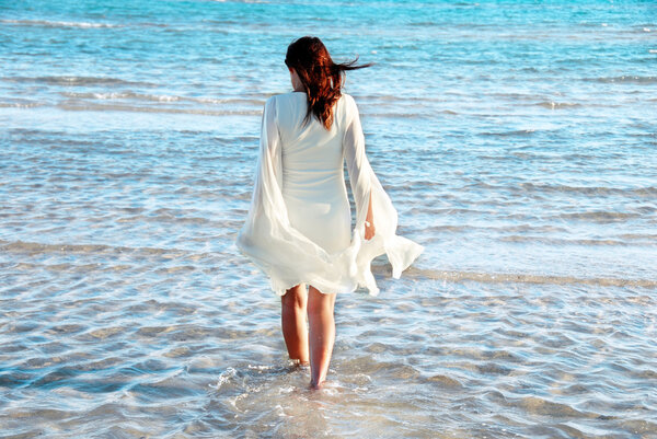 Женщина в белом платье на берегу моря
