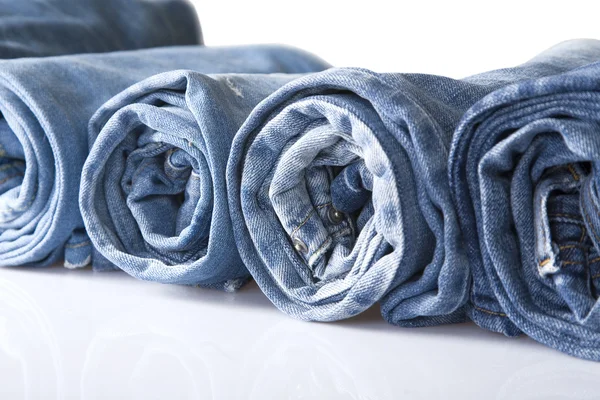 Rulla blå denim jeans arrangerade i linje — Stockfoto