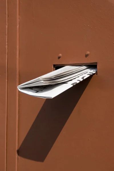 Delivered newspaper on red door — Stock Photo, Image