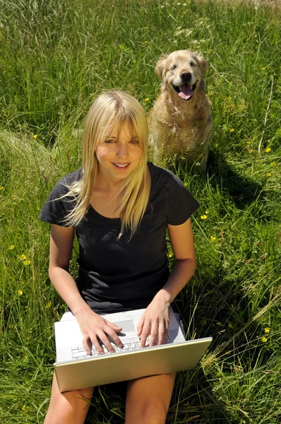 Yong mulher com computador portátil em um prado — Fotografia de Stock