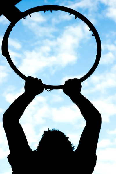 stock image Man hanging on to a basketball hoop