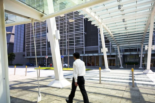 Бизнесмен прогулки в современном здании под открытым небом — стоковое фото