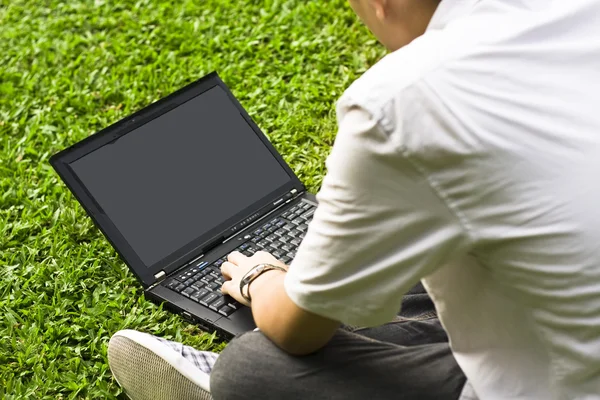Hombre sentado en la hierba usando el ordenador portátil — Foto de Stock