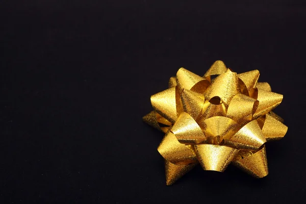 Gold bow on black paper — Stock Photo, Image