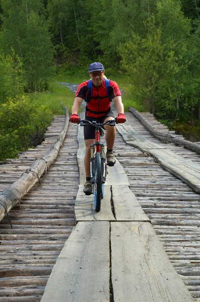 Mountainbiker op houten brug — Stockfoto