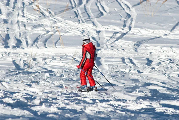 Woman in red and ski traces on snow — Stock Photo, Image