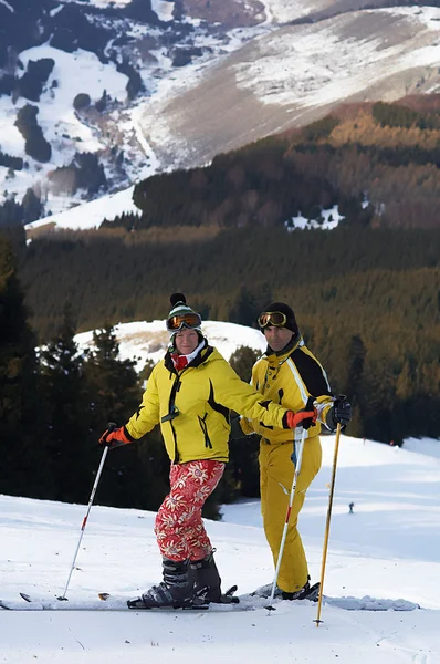 Yong familie skiërs in geel op de skipiste — Stockfoto