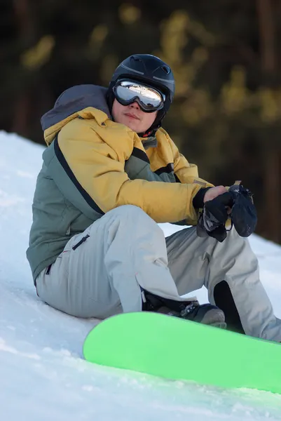 Snowboard man zit op de skipiste — Stockfoto