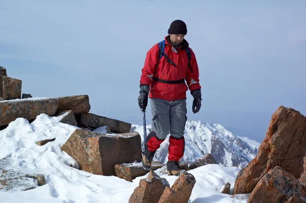 Homem de vermelho viaja na montanha de inverno — Fotografia de Stock