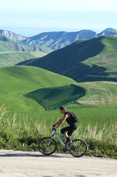 山骑自行车的人和绿山 — 图库照片