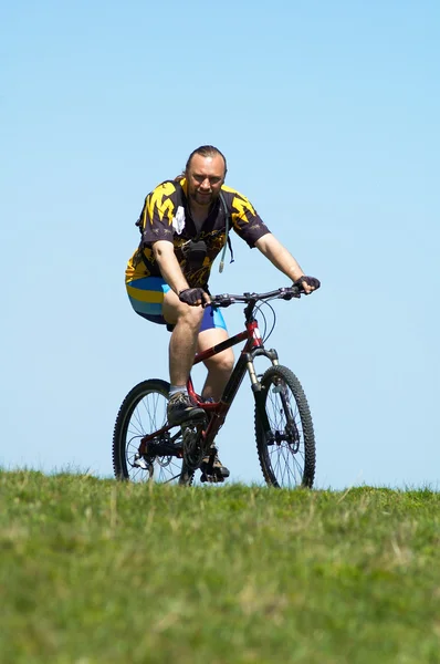 Гірський велосипедист, небо і трава — стокове фото