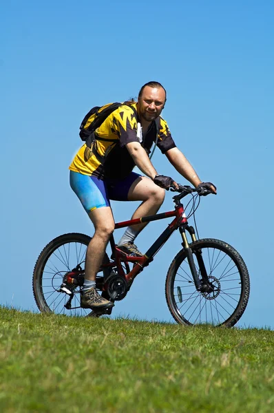 Mountainbiker en gras en hemel — Stockfoto