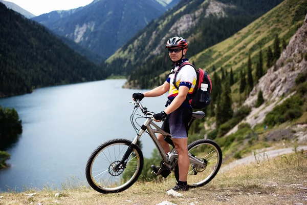 Motociclista ao lado do lago montanha — Fotografia de Stock
