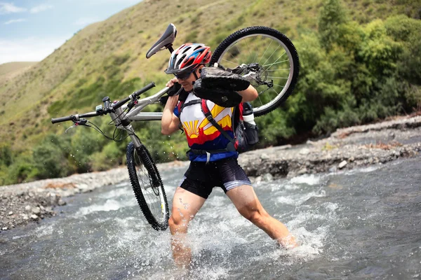 Rowerzysta idzie na górskiej rzece — Zdjęcie stockowe
