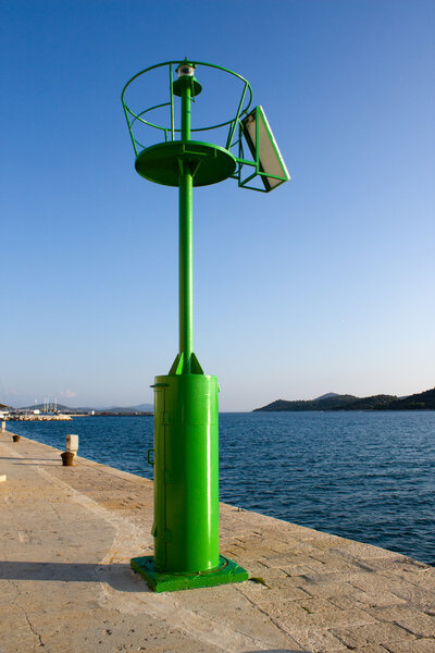 Small green lighthouse on harbor entrance