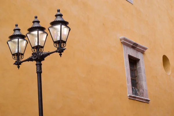 Lâmpada de rua e parede laranja Stucco — Fotografia de Stock