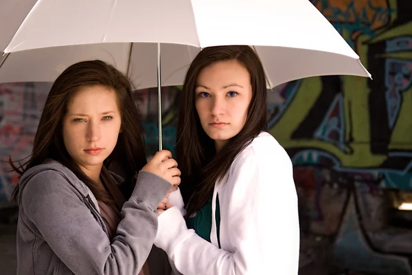 Två tonårsflickor under ett paraply — Stockfoto
