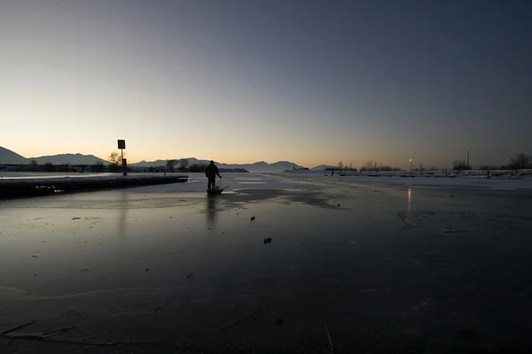 Рыбак тянет сани на льду — стоковое фото