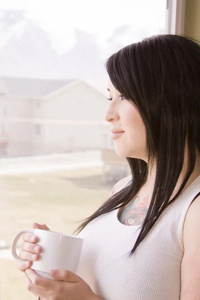 Kvinna vid ett fönster med en kopp — Stockfoto