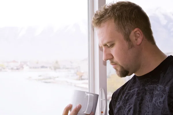 Homem pela janela com uma xícara de café — Fotografia de Stock