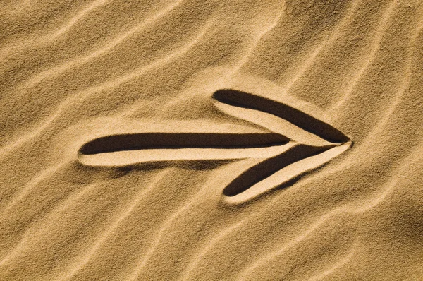 Znak strzałki w piasku — Zdjęcie stockowe