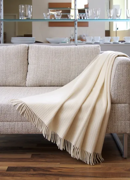 Cremewurf drapiert über ein Sofa — Stockfoto