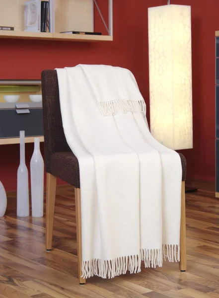 Witte gooien gedrapeerd over een stoel — Stockfoto