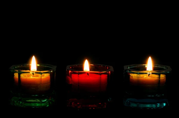 3 aangestoken kaarsen onderrand op zwart. — Stockfoto