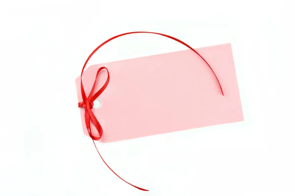 Pretty pink tag with red ribbon on white — Stock Photo, Image