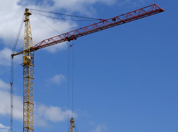 Elevating construction crane against the blue sky in a fair weather