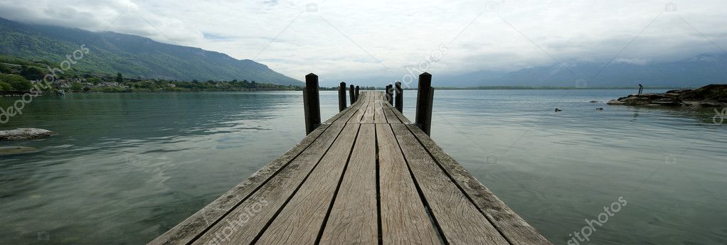 The wooden pier for boats and yachts on the background of the lake water