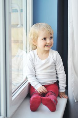 Girl sits at window clipart