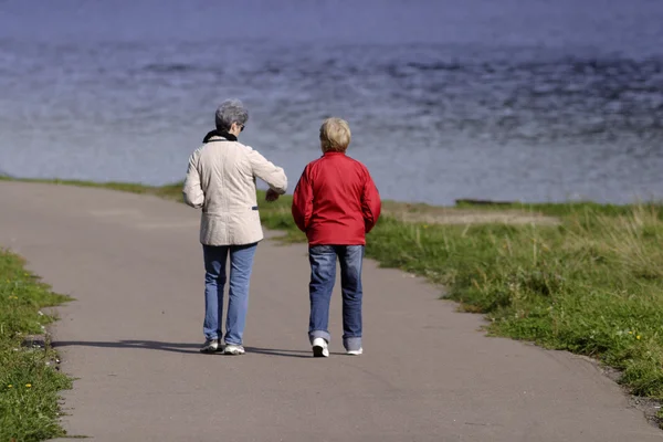 Две зрелые женщины, идущие вдоль реки — стоковое фото