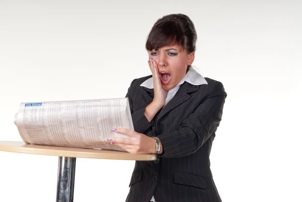 Una joven mujer de negocios leyendo el periódico y sorprendida — Foto de Stock