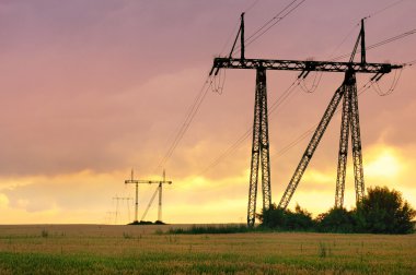 Electric power pylons at sunset clipart