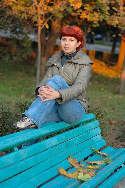 Autumn. Young girl with red hairs seating on ben — Stock Photo, Image