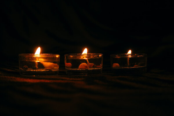 Three decorative candles on dark striped background