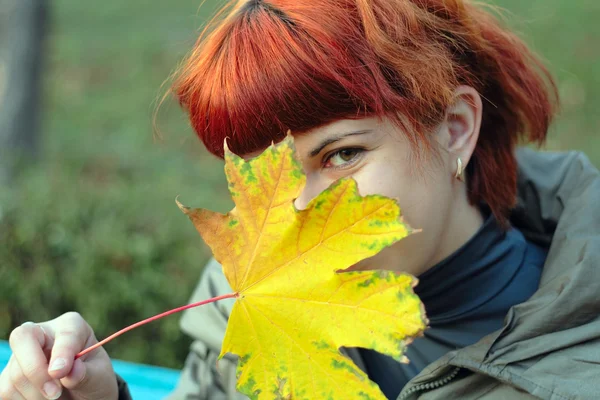 stock image Young woman looking out yellow leave