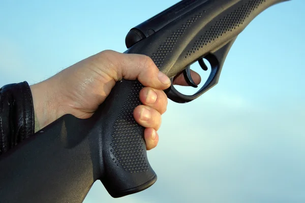 Man hand holding gun over sky — Stock Photo, Image