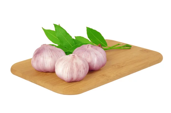 Garlic on the board with a bay leaf. — Stock Photo, Image
