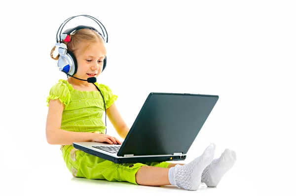 Dizüstü bilgisayar ile kulaklıklar içinde küçük kız — Stok fotoğraf